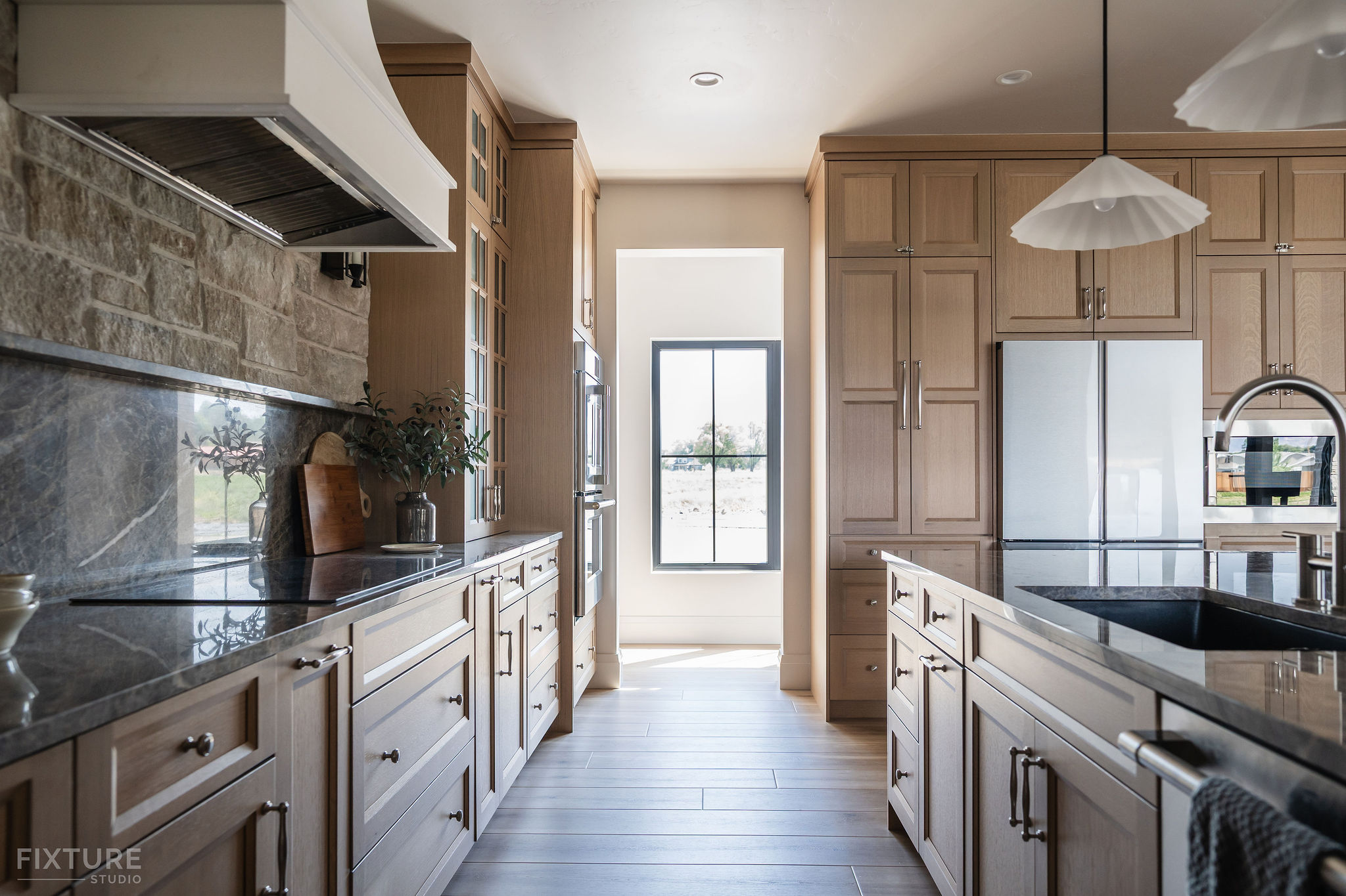 Modern oak kitchen design with stone backsplash, black granite countertops, and custom cabinetry by Fixture Studio.